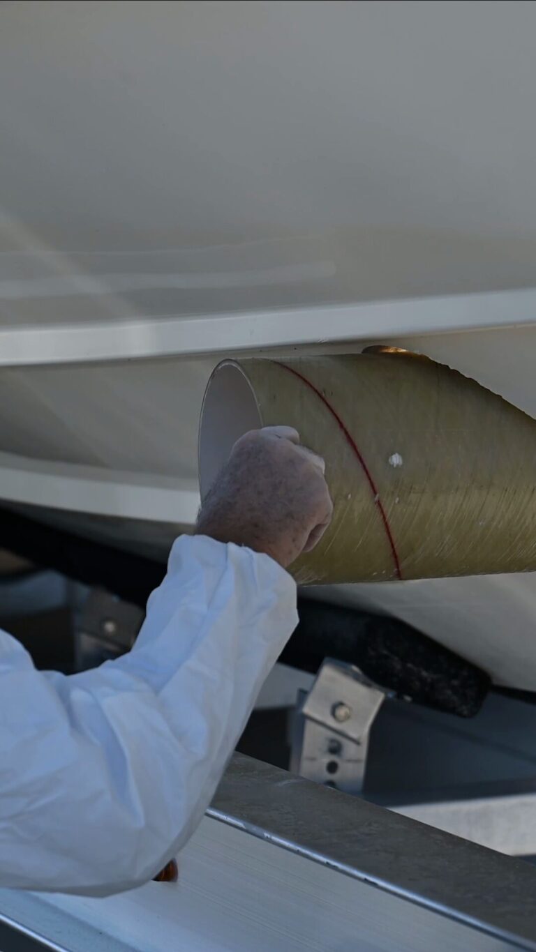 A fiberglass thruster tunnel dry-fitted through the hull of a 35 ft Scarab, marked in red for trimming